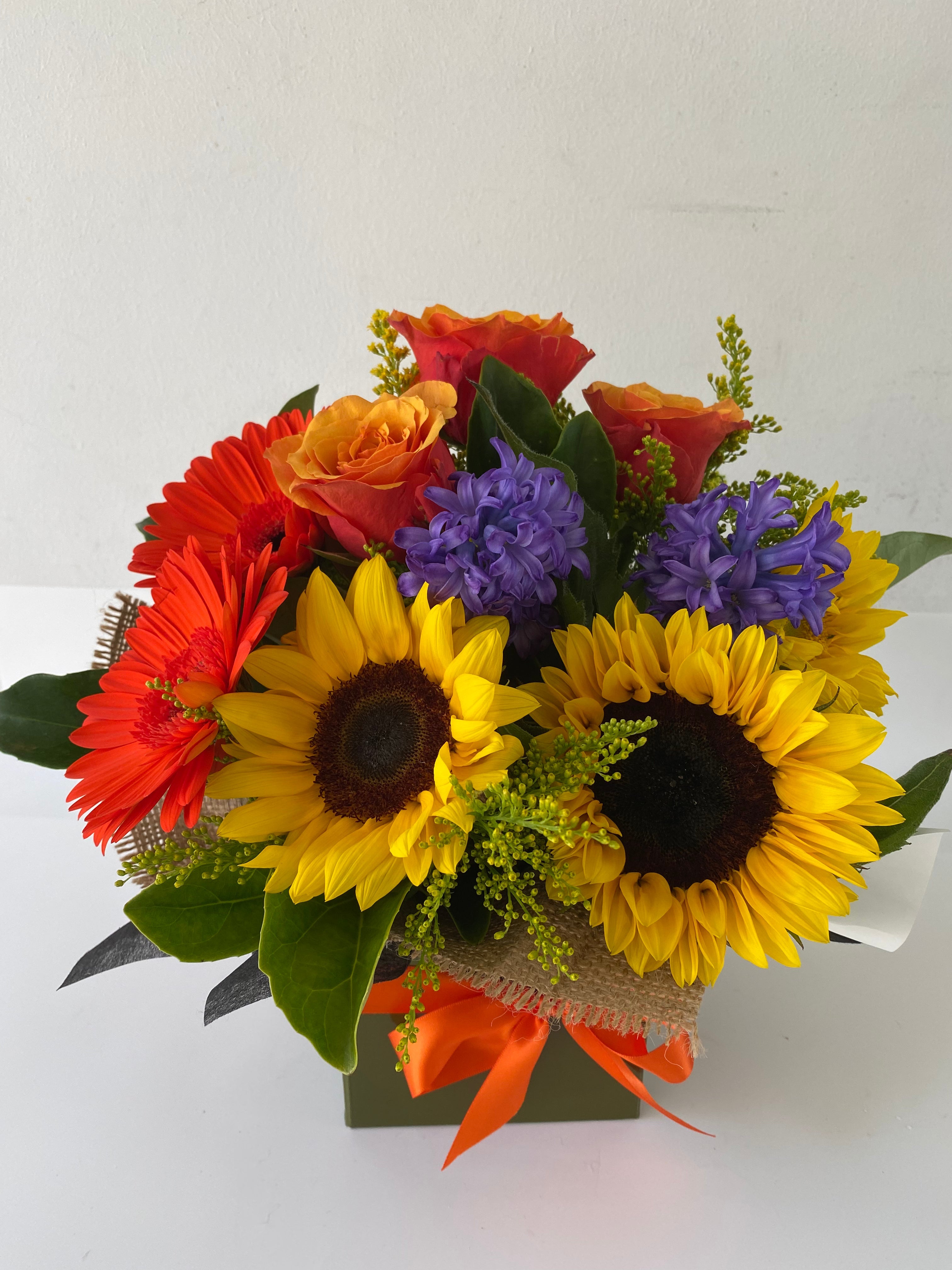 A floral arrangement of sunflowers, gerbera daisies, and other flowers